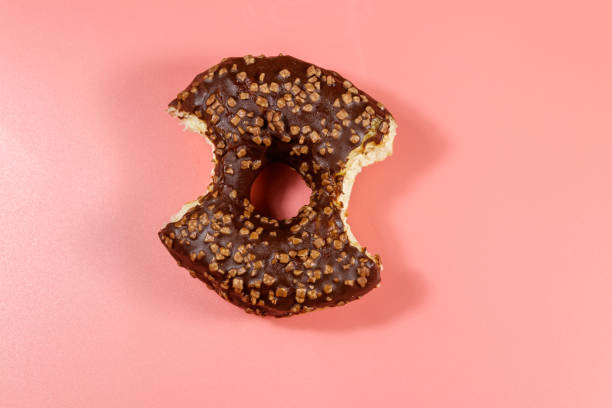 istock Bitten tasty chocolate donut on a pink background. Top view 1302085547