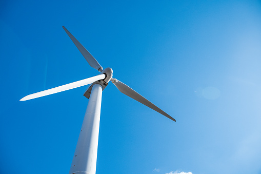 Close up shot of wind mills turbine rotating by the wind and generating renewable green energy. Closeup of a wind turbine during golden hour sunset. Energy alternative and environment ecology.