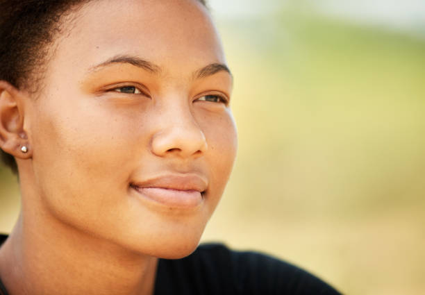 istock Young woman day dreaming and smiling while sitting outside in summer 1302086822