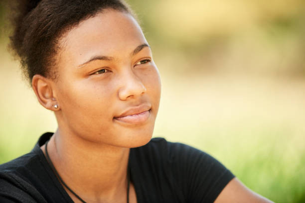 istock Smiling young woman sitting outside deep in thought 1302086823