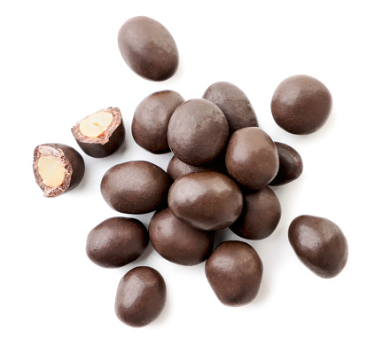Heap of peanuts in chocolate and broken halves on a white background. Top view.