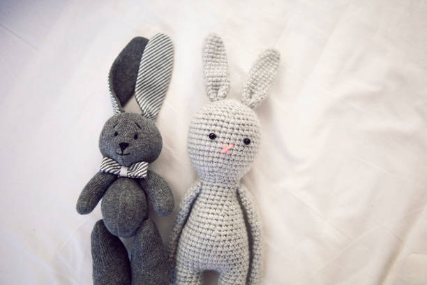 istock two knitted rabbit toys lie under a blanket in a white bed 1302088966