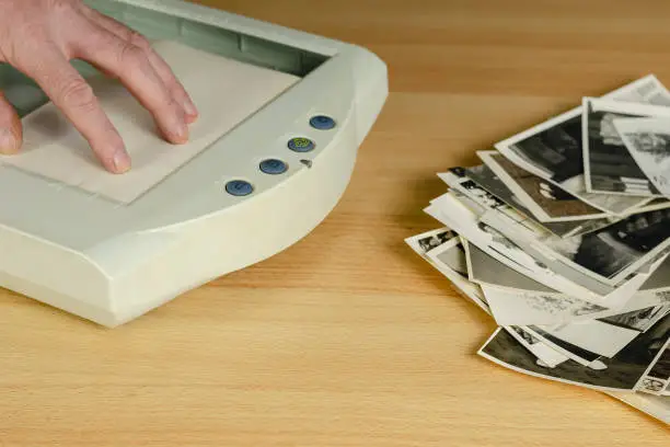 Photo of Scanning old photos. A man's hand puts a photo in the scanner.
