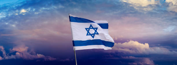Israeli flag with a star of David at cloudy sky background on sunset, panoramic view. stock photo