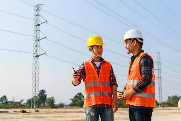 istock Asian engineer manager and foreman or leader discussion and pointing to construction site project on workplace and High voltage power line pylon in the background. Teamwork, Leadership concept. 1302093550