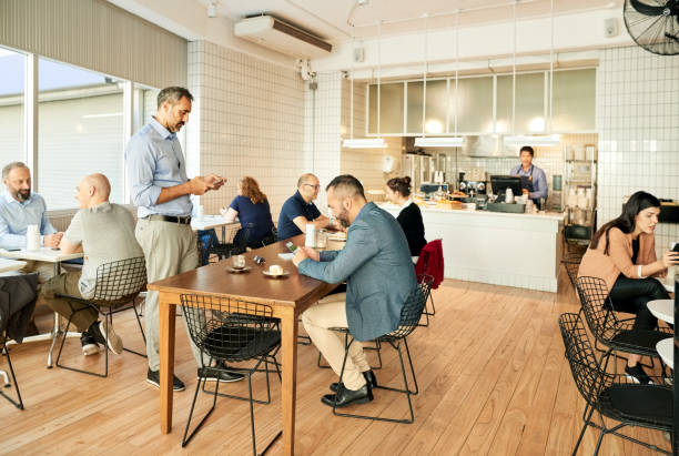 Local coffee shop Shot of a local coffee shop with people sitting at tables busy restaurant tables stock pictures, royalty-free photos & images