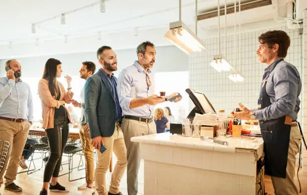 Photo of Barista taking order from people standing in line