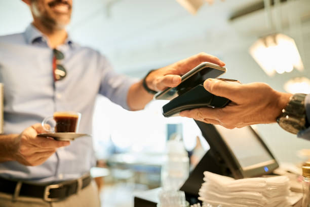 Just tap and pay Cropped shot of a customer paying for coffee with a smartphone at a cafe cash register photos stock pictures, royalty-free photos & images