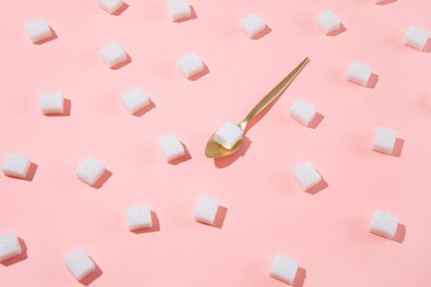 Geometry Pattern Made of White Sugar Cubes on Pink Background Geometrical pattern with white sugar cubes and a teaspoon on pastel pink background sugar cube stock pictures, royalty-free photos & images