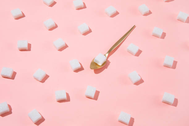 Geometry Pattern Made of White Sugar Cubes on Pink Background Geometrical pattern with white sugar cubes and a teaspoon on pastel pink background Sugar stock pictures, royalty-free photos & images