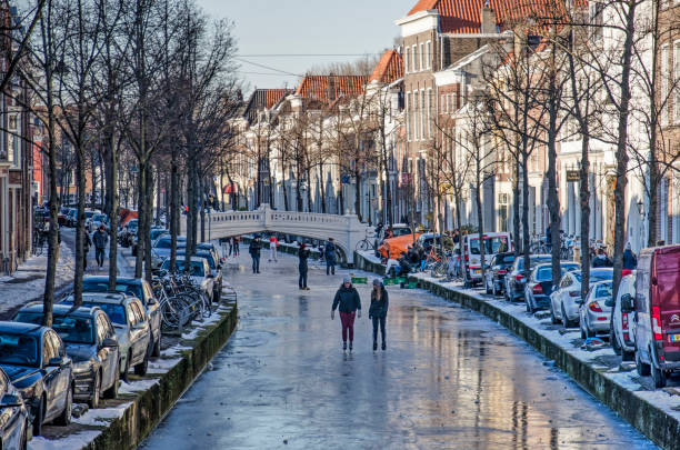 Skating on a Delft canal Delft, The Netherlands, February 13, 2021: people skating on the ice on Voorstraat, one of the frozen canals in the old town delft winter netherlands snow stock pictures, royalty-free photos & images