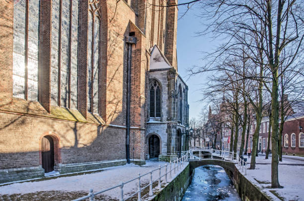 Delft church and canal in winter Delft, The Netherlands, February 13, 2021: the old church and Oude Delft canal on a sunny day in winter delft winter netherlands snow stock pictures, royalty-free photos & images