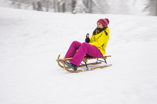 Young woman playing with a vintage sledding in mountain