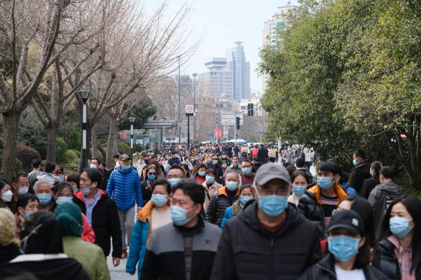 crowded chinese people walking on street in face mask - china covid imagens e fotografias de stock