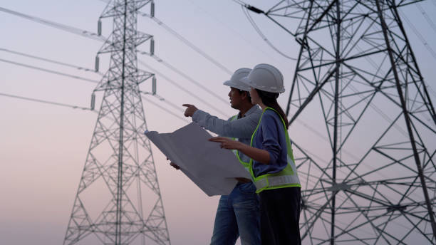 deux ingénieurs électriciens spécialisés travaillant près de la tour à haute tension. - réseau électrique photos et images de collection