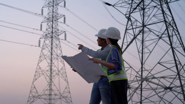 Two specialist electrical engineer working near to High voltage tower. Two specialist electrical engineer working near to High voltage tower. electrical grid stock pictures, royalty-free photos & images