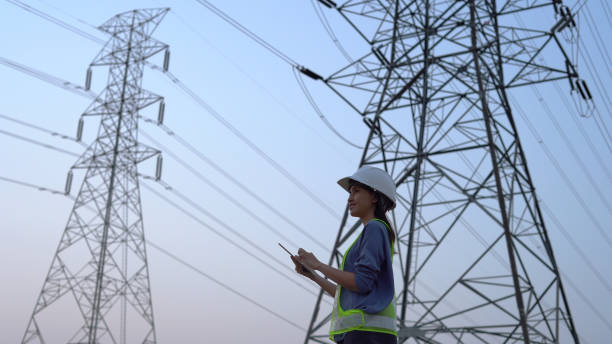 Female electrical engineer working near to High voltage tower. stock photo