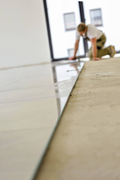 istock Professional worker in work clothes on the ground laying tiles in a living room of a new apartment 1302103473