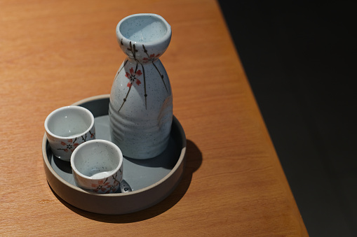 Traditional Japanese sake bottle and cup on wooden table. Black copy space
