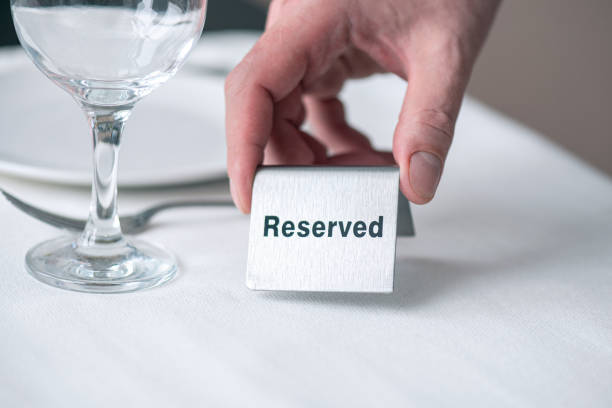 istock A waiter holding iron sign with text reserved on table with white tablecloth at restaurant 1302104626
