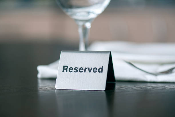 signo de hierro reservado en la mesa de madera frente al mantel blanco y copa de vino en una cafetería o restaurante - wildlife reserve fotografías e imágenes de stock