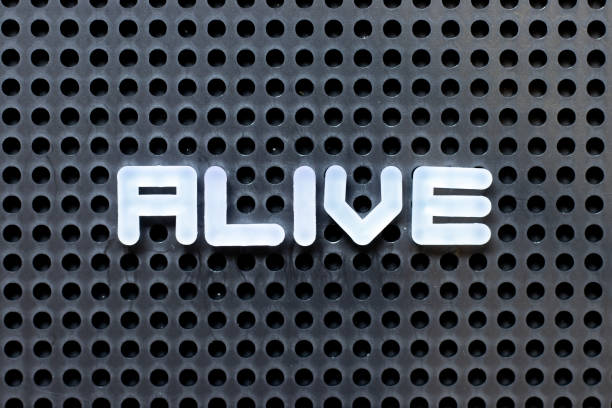 White color alphabet with word alive on black pegboard background