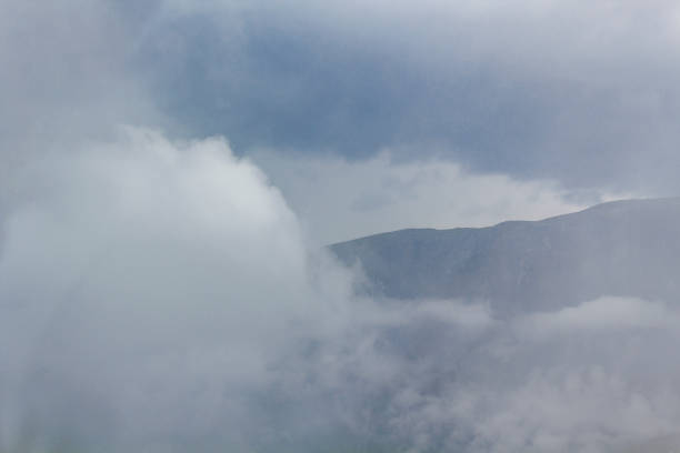 Fog mist clouds rain and waterfall on mountain in norwegian landscape Jotunheimen National Park Norway.