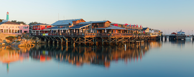Early morning panoramic view of the Monterey Fisherman's wharf and its reflection in Monterey bay (Monterey, California).