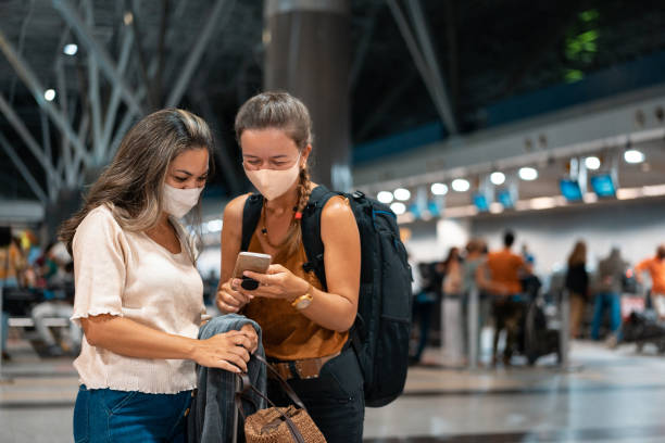 istock Women using smartphone at the airport during pandemic 1302113543