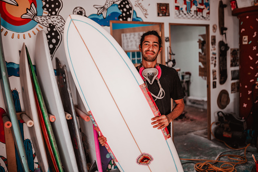 Young man proudly holding his new crafted surfboard