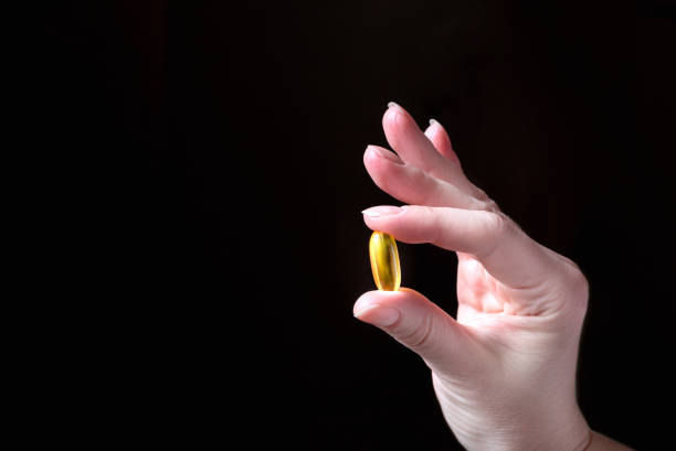 istock Human hand in ok gesture holds golden pill. Dark background 1302114752