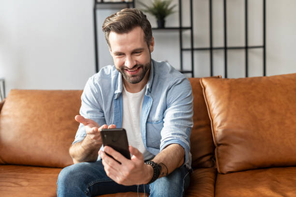 istock Handsome bearded guy wearing casual shirt using a phone 1302116021