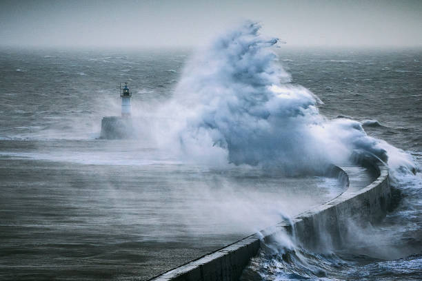 istock Stormy seas with huge waves breaking over a sea wall 1302118573