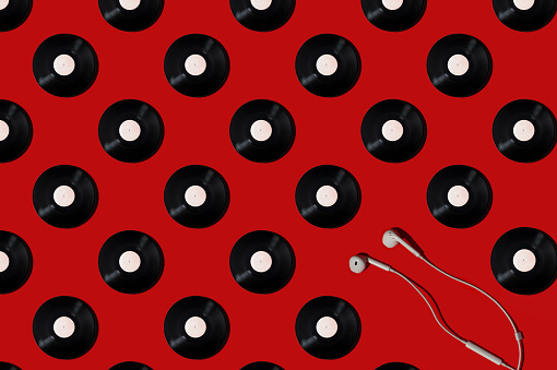 Pattern of vinyl records and earphones on a red background. Minimal trendy composition