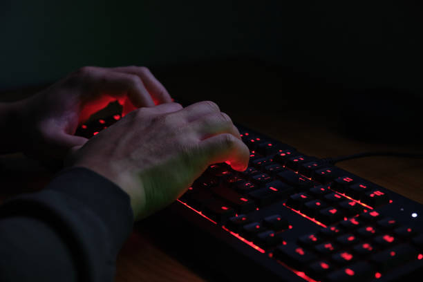 istock Hands typing on a red lighting keyboard on dark background. Cyber criminal concept. 1302118658
