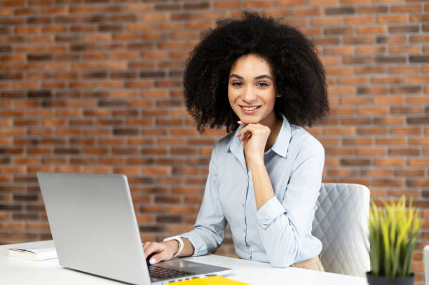 istock Young businesswoman sitting in front of computer and posing at camera 1302119664