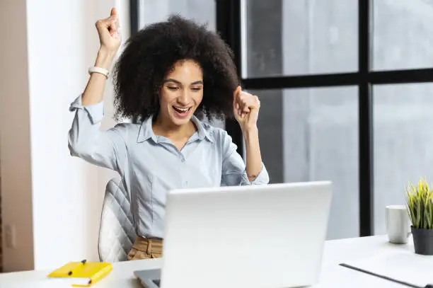 Photo of Lucky mixed-race businesswoman raised fists up