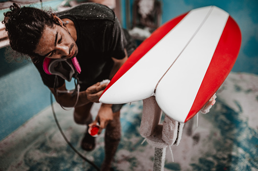 Young man focusing on the details on the surfboard