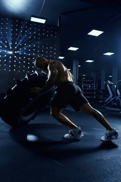 istock Man moving giant tire wheel in gym. 1302127459