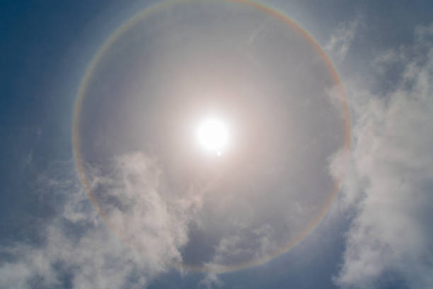 Sun halo with circular rainbow and little cloud sun halo occurring due to ice crystals in atmosphere sundog stock pictures, royalty-free photos & images