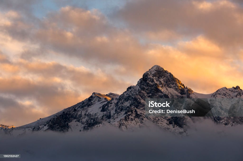 Mountain Above The Clouds A peak in the Sneffels Range, S9 peeks out of the clouds in time to shine in the setting sun. Mountain Peak Stock Photo