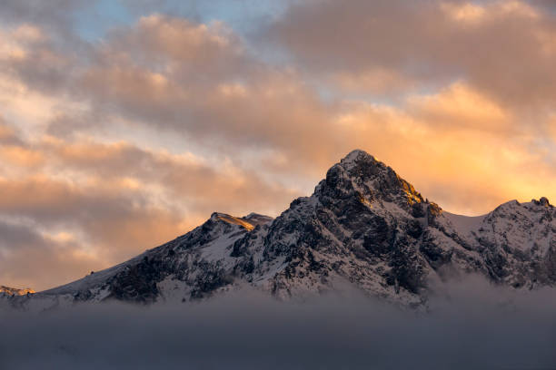 Mountain Above The Clouds A peak in the Sneffels Range, S9 peeks out of the clouds in time to shine in the setting sun. ridgway stock pictures, royalty-free photos & images