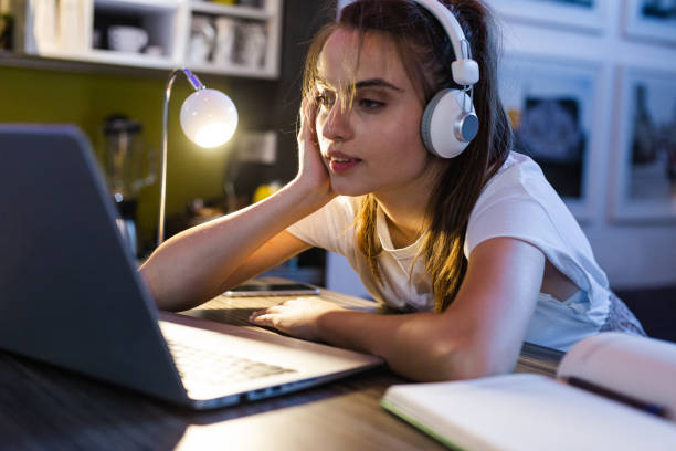 istock Tired girl is doing homework on her laptop 1302132655