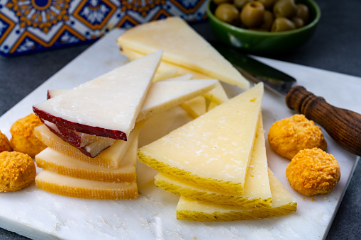 Spanish snacks tapas, variety of sliced goat, sheep, manchego cheeses, green olives, served in Andalusian interior