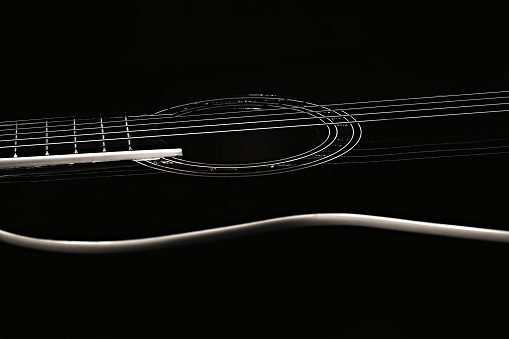 An acoustic guitar stands against a scratched wall against a dark background. Background for the screen saver with a musical instrument.