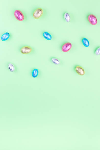 istock Green paper texture with colorful chocolate candy eggs, Easter background, vertical, copy space 1302136857