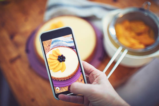 Someone photographs the half-finished fruit cake with their smartphone Someone photographs the half-finished fruit cake with their smartphone custard photos stock pictures, royalty-free photos & images