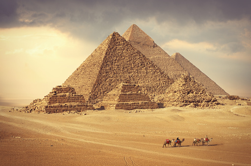 Famous pyramids in Giza and camel caravan in the desert