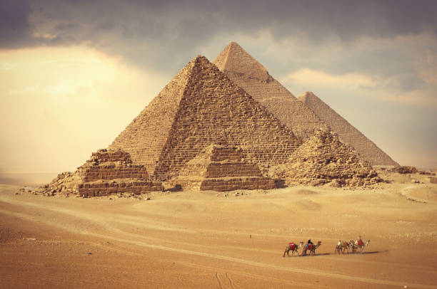 Pyramids in Giza and camel caravan Famous pyramids in Giza and camel caravan in the desert kheops pyramid photos stock pictures, royalty-free photos & images