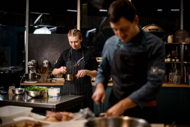 istock view on young attractive woman chefs in restaurant kitchen preparing dish. 1302139292